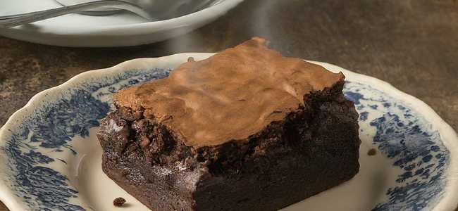 Chocolate brownie on plate by tea.