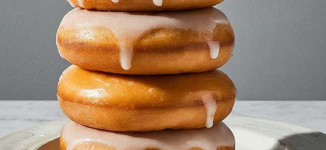 Four glazed donuts on plate.