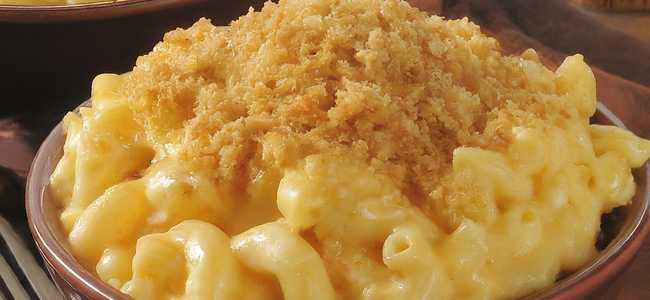 Macaroni and cheese in a bowl with a fork sitting next to the bowl.